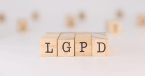 Blocos de madeira alinhados formando a sigla LGPD em destaque sobre um fundo desfocado.