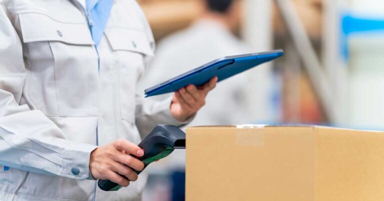 Profissional utilizando leitor de código de barras e tablet para monitorar embalagem, simbolizando rastreabilidade de produtos e controle logístico.