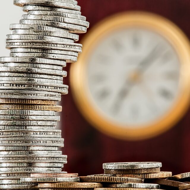Na imagem, o crescimento proporcionado pelo ERP financeiro está representado nas colunas crescentes de moedas empilhadas, com o relógio de fundo.