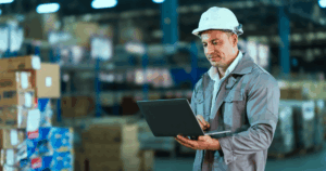 Profissional utilizando EPI com notebook em mãos analisando a capacidade produtiva