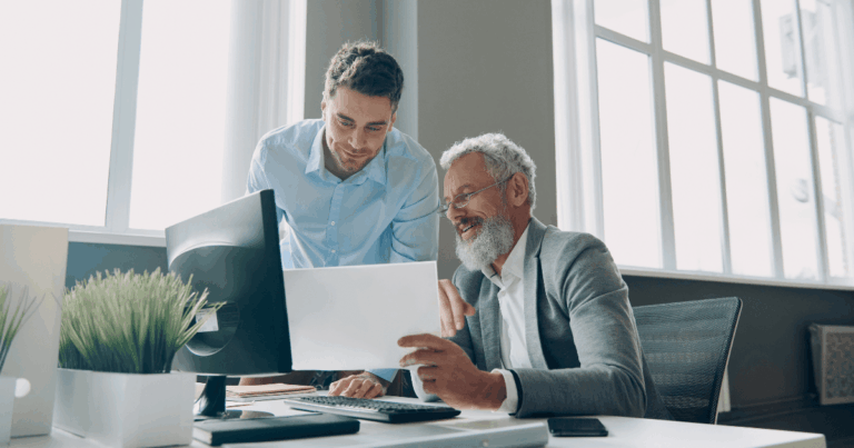 Dois profissionais analisando documentos em escritório, representando a colaboração entre áreas na gestão eficiente da cadeia de valor empresarial.