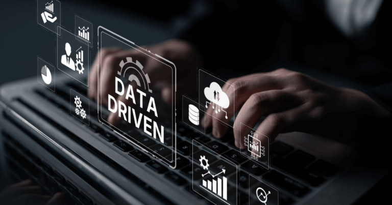 Pessoa digitando em um notebook com interface digital sobreposta exibindo gráficos, ícones de nuvem, engrenagens e a expressão “data driven”, representando tomada de decisão orientada por dados e análise estratégica.