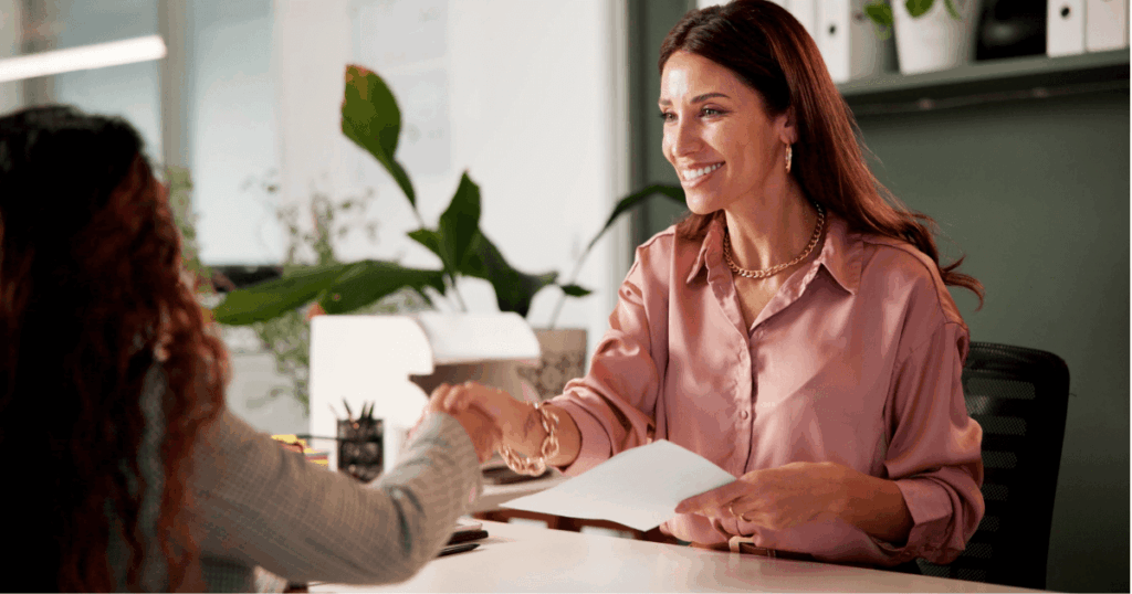 Duas mulheres profissionais cumprimentando-se, ilustrando integração e onboarding profissional.