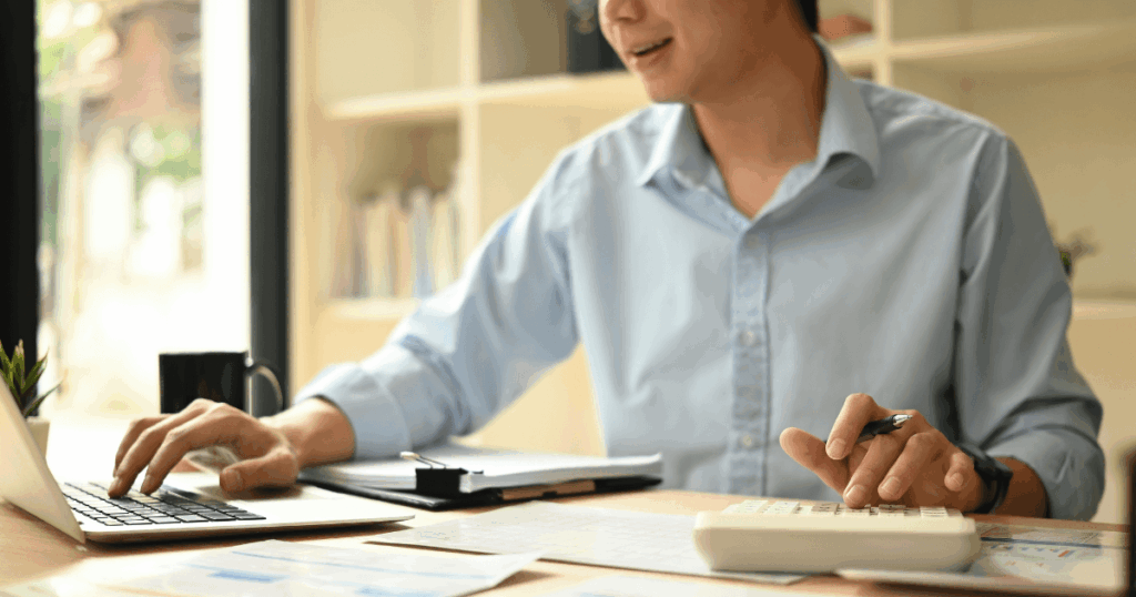 Profissional analisando documentos fiscais e realizando cálculo das informaçõesusando uma calculadora