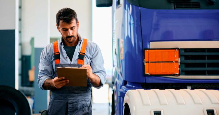 Homem analisando prancheta ao lado de caminhão em oficina, representando o controle e execução de uma ordem de serviço