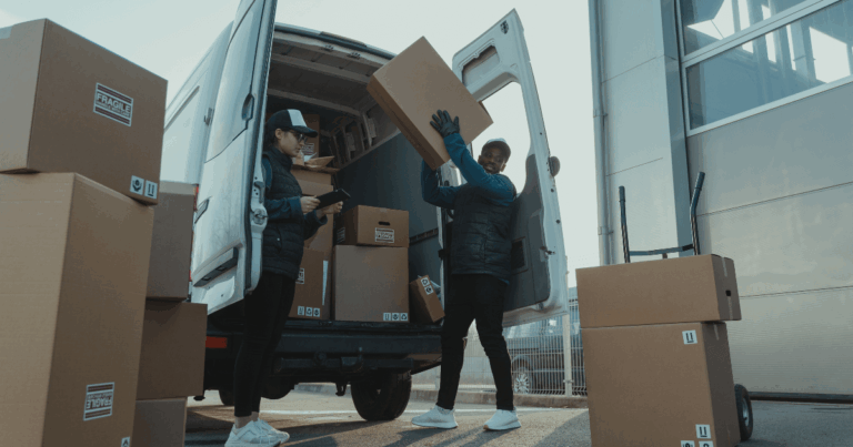 Equipe de logística carregando mercadorias em van de transporte, representando o processo de distribuição e entrega na operação triangular entre empresas.