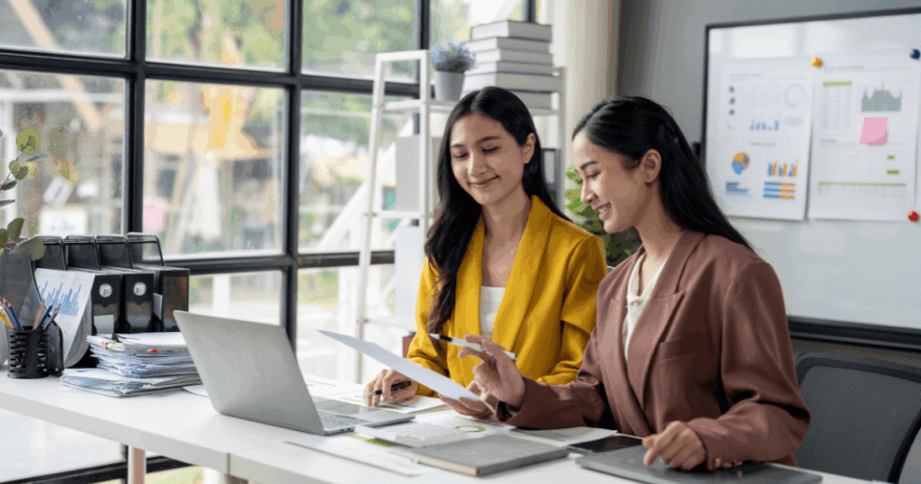 Duas profissionais analisando documentos e gráficos em ambiente corporativo, representando o uso da inteligência tributária.