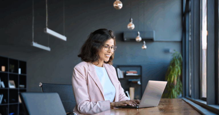 Profissional de RH sorridente usando notebook em um escritório moderno, representando o uso da IA no RH para otimizar processos e melhorar a experiência dos colaboradores.