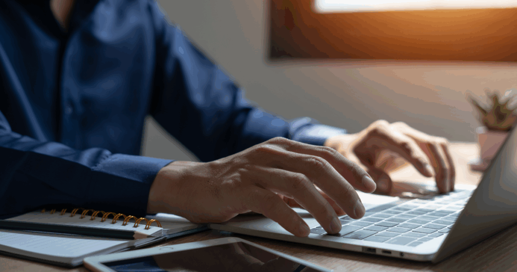 Profissional digitando em um notebook, realizando o preenchimento do PGDAS-D