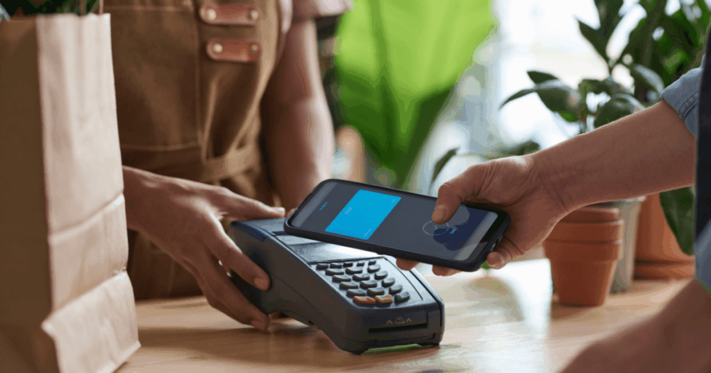 Pagamento por aproximação via smartphone em maquininha, representando soluções de Embedded Finance no varejo.