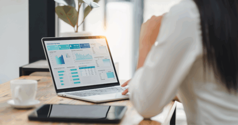 Profissional analisando gráficos e indicadores de desempenho em um notebook, representando estratégias de gestão de dados em ambiente corporativo.