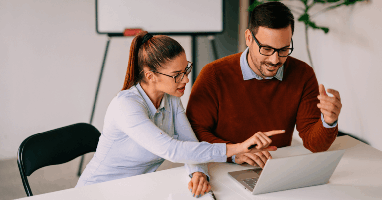 Profissional de negócios explicando estratégias em laptop para colega, ilustrando conceito de lucratividade e rentabilidade em ambiente corporativo.
