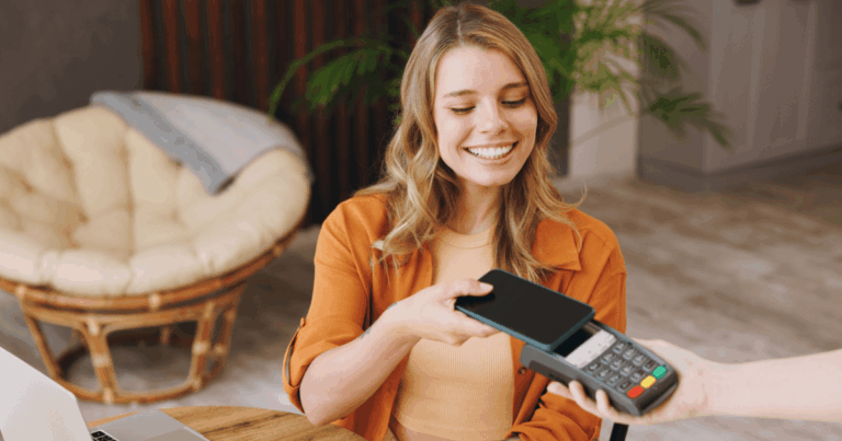 Mulher sorridente realizando pagamento por aproximação com celular, representando o uso do Pix parcelado no varejo moderno