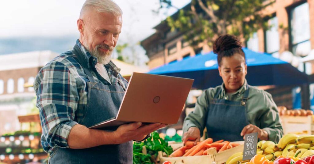 Produtores rurais organizando vendas e controle financeiro com uso de tecnologia, representando a importância da gestão integrada e da tributação rural com apoio de ERP.