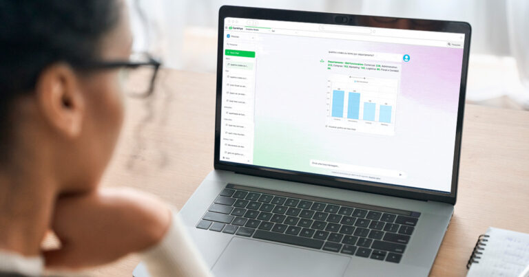 Profissional analisa gráficos de desempenho no sistema Sankhya Analytics AI em um notebook, destacando o uso de inteligência artificial no ERP para tomada de decisões estratégicas por departamento.