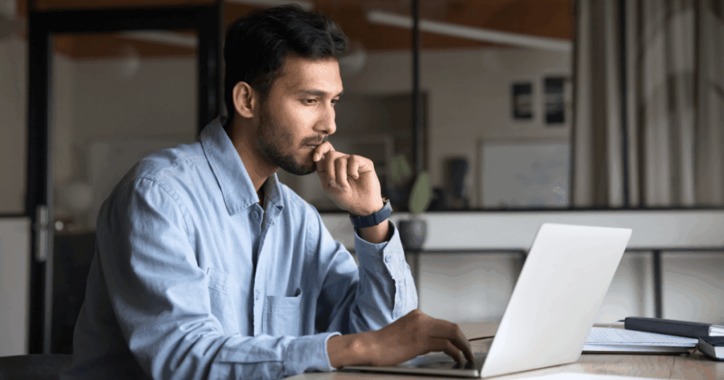 Profissional trabalhando em seu computador, refletindo sobre questões relacionadas ao absenteísmo no ambiente de trabalho, buscando soluções para melhorar a presença e o desempenho da equipe.