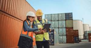 Trabalhadores em área industrial utilizando EPIs e analisando dados em um tablet, simbolizando ações do GRO Gerenciamento de Riscos Ocupacionais para prevenção de acidentes no ambiente de trabalho.