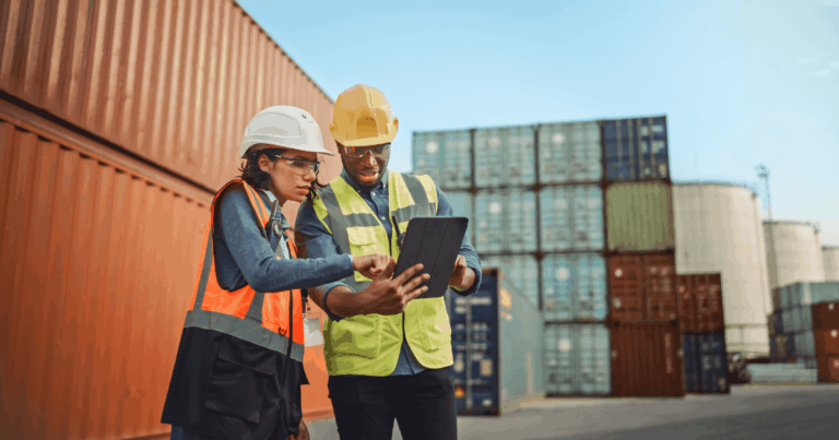 Trabalhadores em área industrial utilizando EPIs e analisando dados em um tablet, simbolizando ações do GRO Gerenciamento de Riscos Ocupacionais para prevenção de acidentes no ambiente de trabalho.