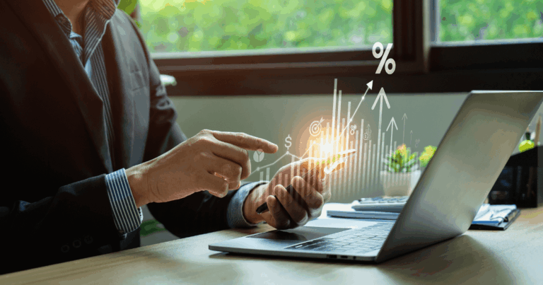 Profissional analisando dados e gráficos de vendas em um relatório, com ícones financeiros e gráficos de crescimento sendo projetados em um smartphone enquanto ele interage com um laptop