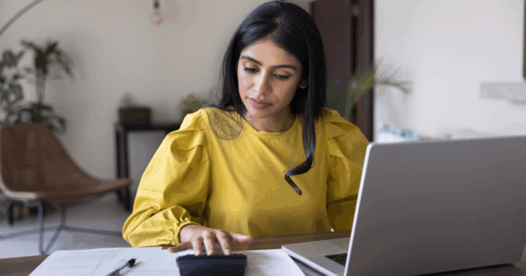 Profissional feminina em um ambiente de escritório calculando a margem de lucro em uma calculadora.