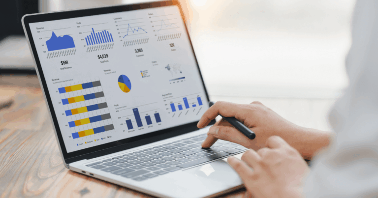 Pessoa analisando gráficos e relatórios de indicadores de desempenho em um notebook, representando a análise de resultados e métricas empresariais.