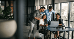 Equipe reunida em um escritório analisando resultados no notebook, representando o uso de OKR para alinhar metas e acompanhar o desempenho organizacional.