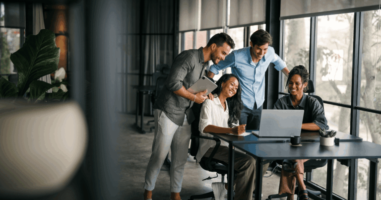Equipe reunida em um escritório analisando resultados no notebook, representando o uso de OKR para alinhar metas e acompanhar o desempenho organizacional.