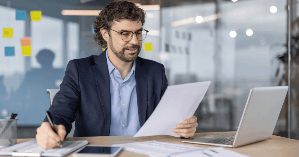 Profissional analisando documentos e registrando informações no escritório, representando o processo de criação e conferência de uma ordem de compra.