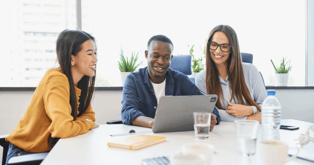 Equipe de profissionais reunida em escritório analisando um plano de treinamento em tablet durante reunião colaborativa.