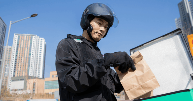 Homem realizando entrega de comida, com mochila de entrega, vestido com roupas de trabalho e capacete. A imagem ilustra o cotidiano de um nanoempreendedor, como entregador de aplicativos, que gerencia seu próprio negócio de forma independente.