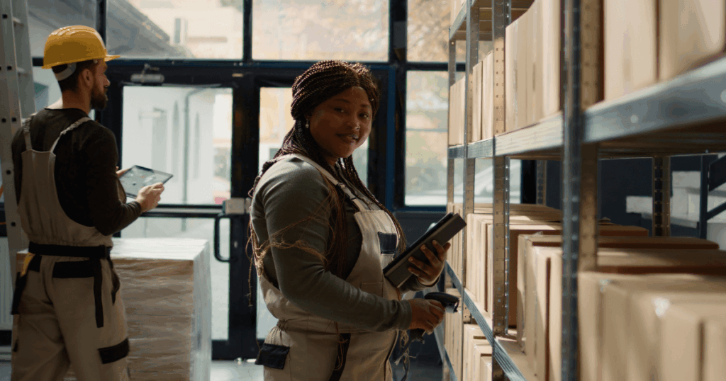 Colaboradores em armazém realizando inventário rotativo, conferindo caixas nas prateleiras com uso de tablet e coletor de dados.