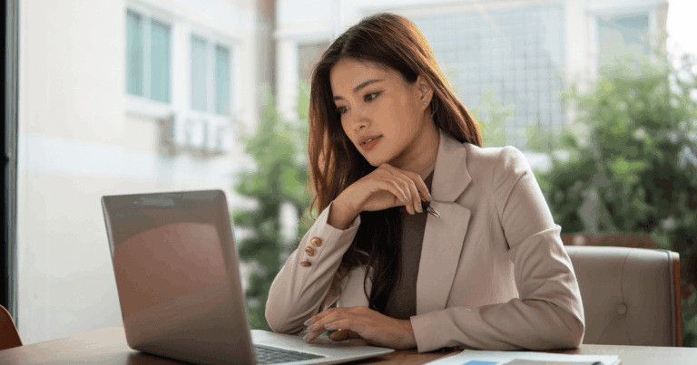 Mulher profissional analisando dados em um laptop em ambiente de escritório, representando estudo ou tomada de decisão financeira relacionada a spread cambial
