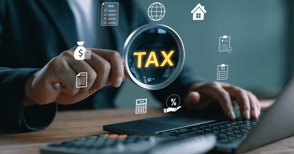 Profissional analisando impostos estaduais no computador com lupa destacando a palavra tax e ícones de tributos ao redor.