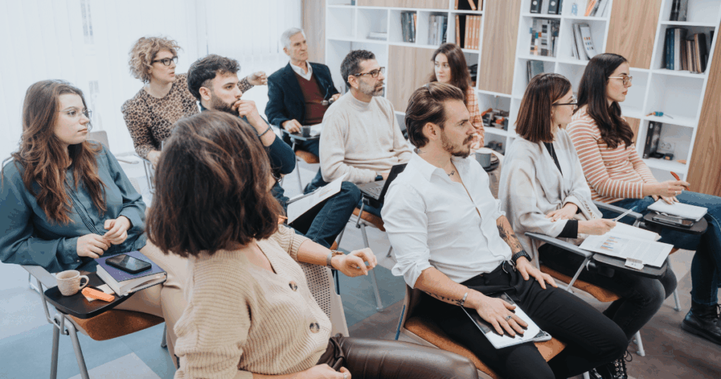 Colaboradores em treinamento empresarial com materiais e dispositivos digitais, representando a aprendizagem contínua nas empresas apoiada por tecnologia e plataformas LMS