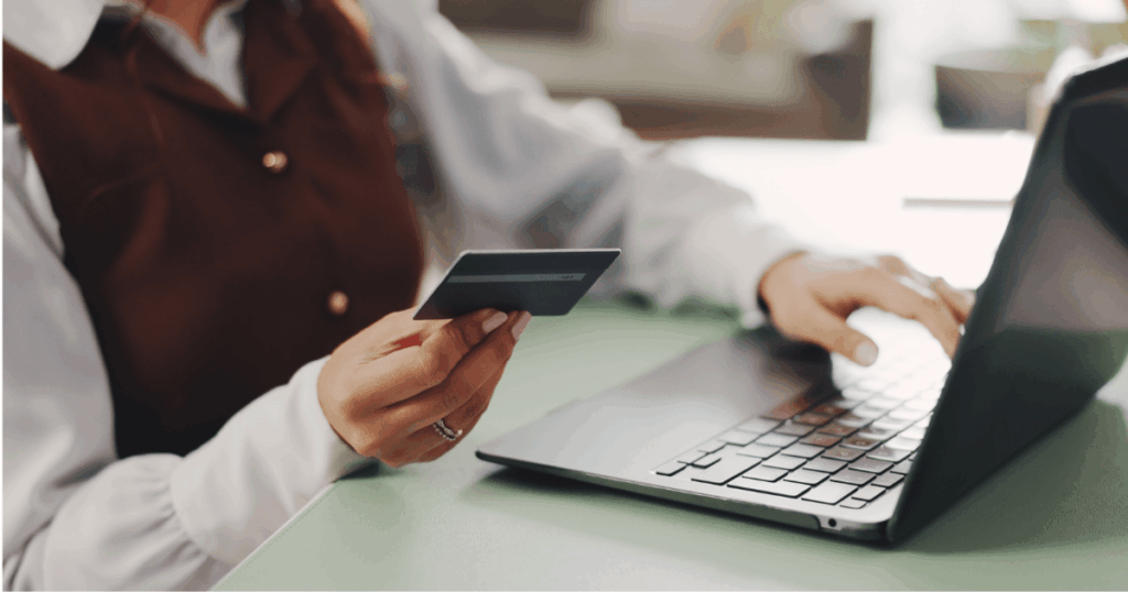 Profissional utilizando um cartão multibenefícios enquanto acessa o laptop, representando a gestão moderna de benefícios e o uso de tecnologia no ambiente corporativo.