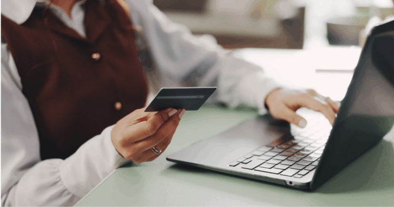 Profissional utilizando um cartão multibenefícios enquanto acessa o laptop, representando a gestão moderna de benefícios e o uso de tecnologia no ambiente corporativo.