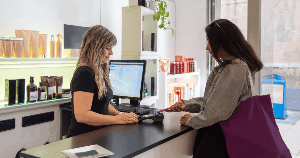 Cliente realizando pagamento no caixa de uma loja de cosméticos enquanto é atendida por uma vendedora, representando estratégias de vendas para o varejo no Dia das Mães
