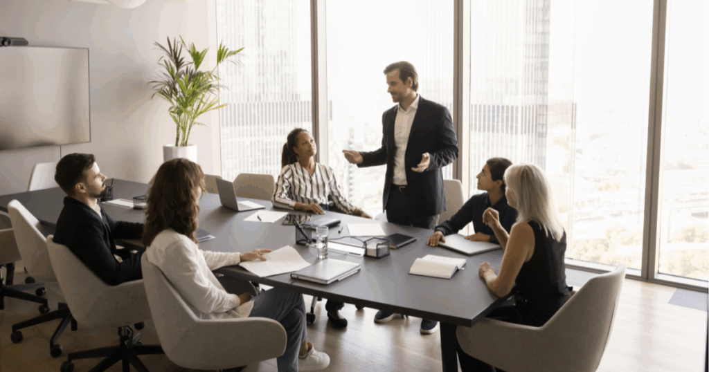 Equipe participando de treinamento corporativo com apoio de notebook em ambiente de trabalho colaborativo.