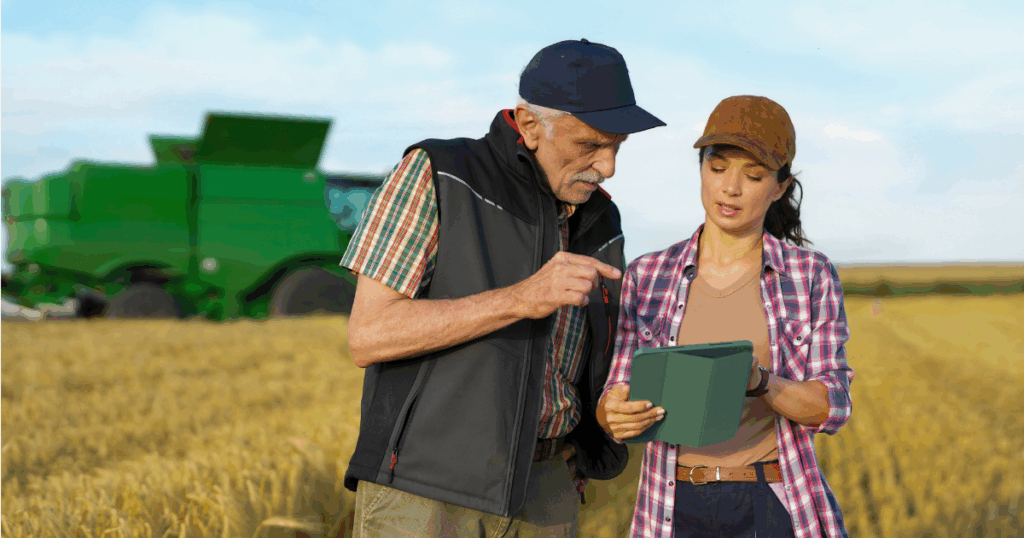 Produtor rural e consultora analisam informações em um tablet durante a colheita em uma lavoura de grãos, com uma colheitadeira ao fundo, representando a gestão financeira e o controle do fluxo de caixa rural